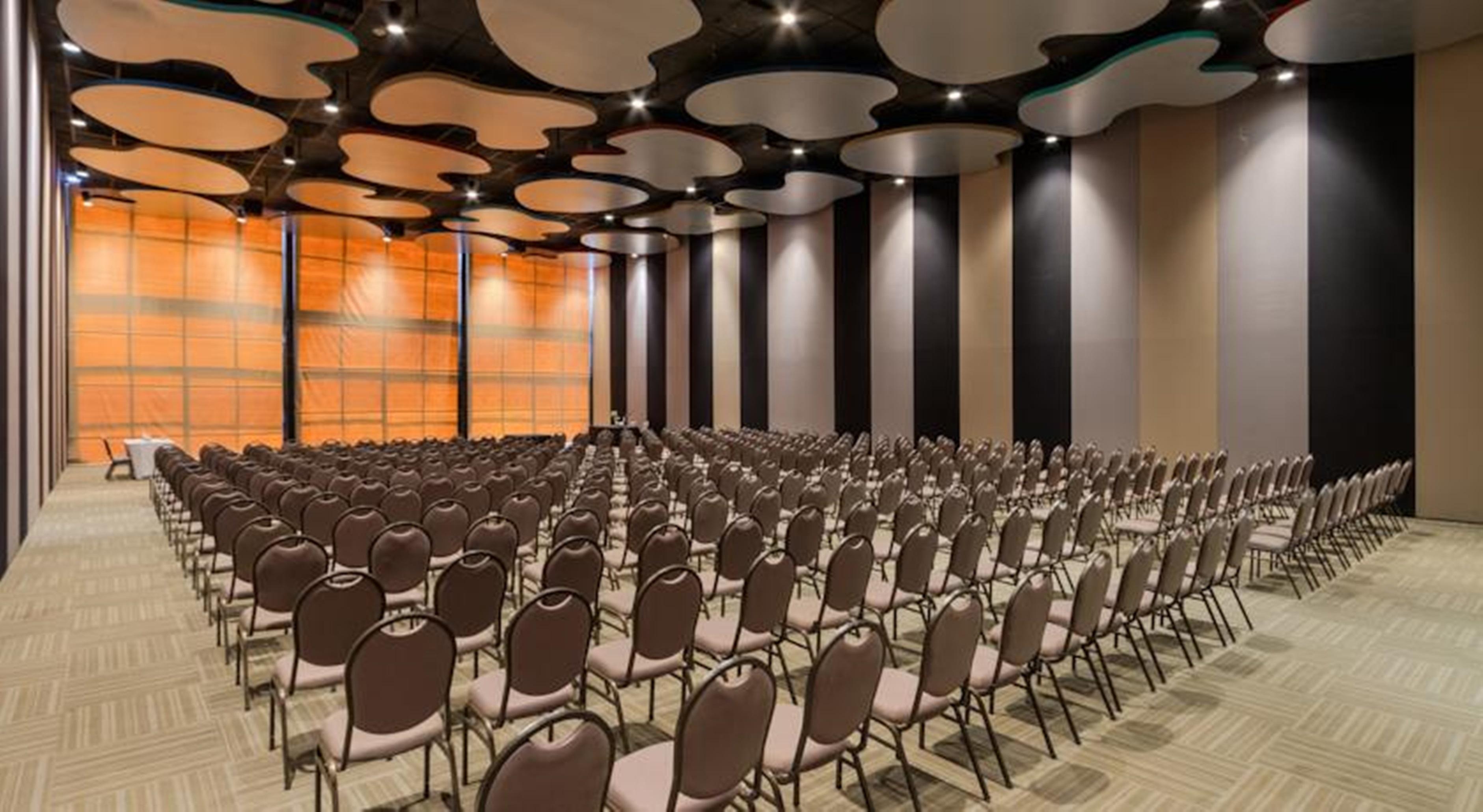 ホテル ロイヤル チューリップ ブラジリア アルボラーダ エクステリア 写真 The photo shows a large conference or event space filled with numerous empty chairs arranged in rows. The chairs have a simple design, with cushioned seats and backs. The walls of the room are decorated with a combination of dark and light tones, and